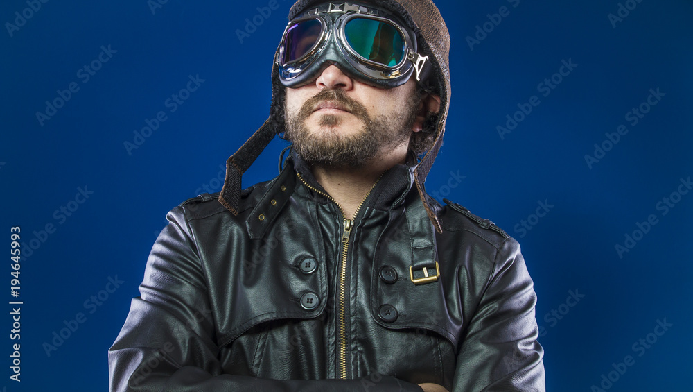 Proud, pilot of the 20s with sunglasses and vintage aviator helmet. Wears leather jacket, beard and expressive faces