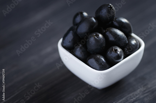 Olives in a white bowl on a dark wooden table
