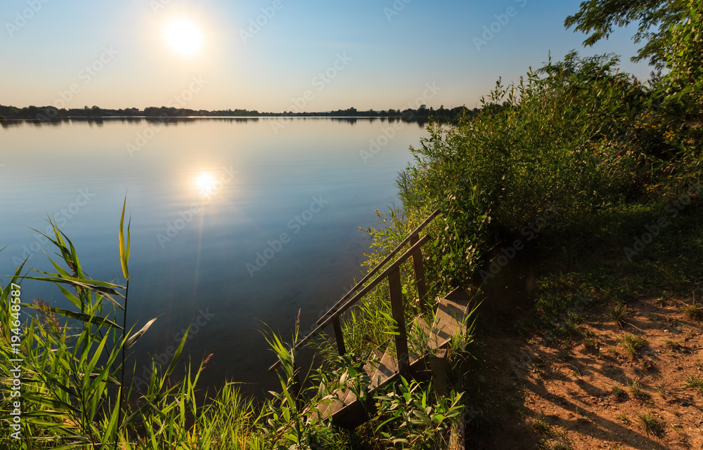 Wooden stairs to summer sunset lake