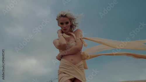 Lonely beautiful woman is looking like a fallen angel without wings. She is walking in a desert, touching her naked shoulders, looking in camera sensually