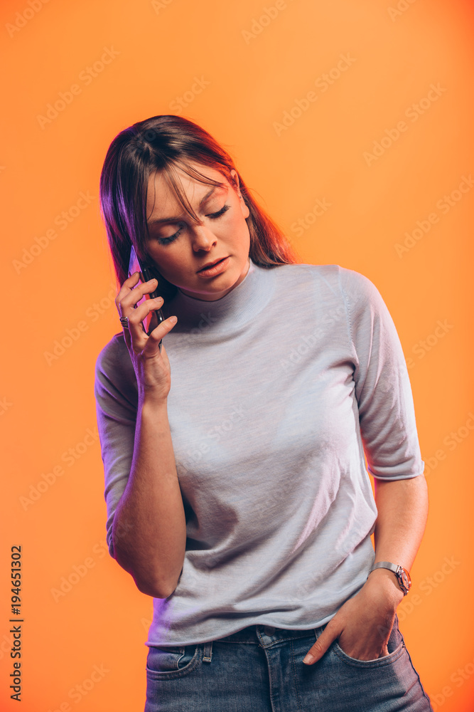 Concentrated young woman calling by mobile phone on yellow background Concentrated young woman calling by mobile phone on yellow background