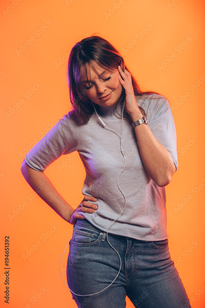 Happy young woman with headphone on orange background Happy young woman with headphone on orange background