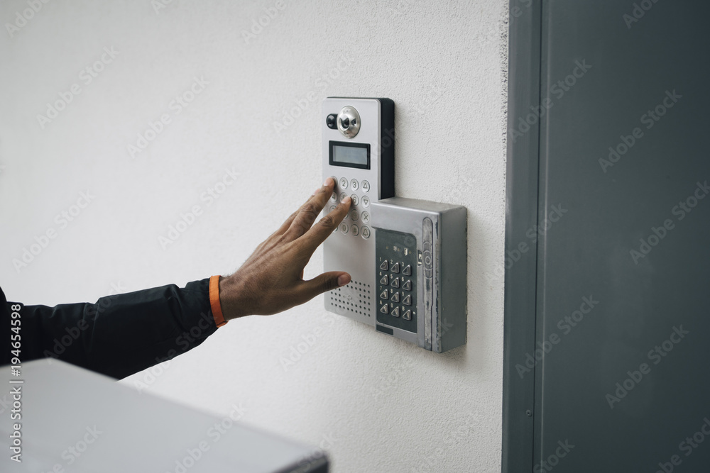Cropped image of delivery man ringing intercom on wall Cropped image of delivery man ringing intercom on wall