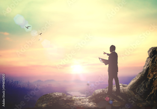 World environment day concept: Businessman hike on the peak of rocks mountain at autumn sunset photo