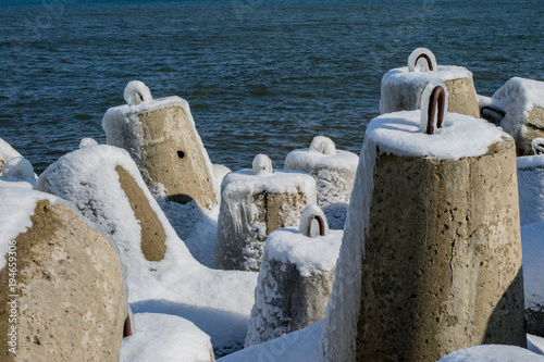 Baltic Sea in Poland. Entrance to the port, ice-covered concrete breakwater.