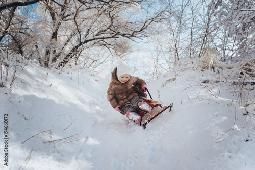 The litle girl is riding a sled. The child falls from the sled. Winter walks children with parents. Extreme, adrenaline, danger. © shchus