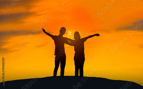 Man and woman in love. They are standing and see the sun set. Woman wearing a hatand man Man hugging woman.Photo concept Silhouette and love. 