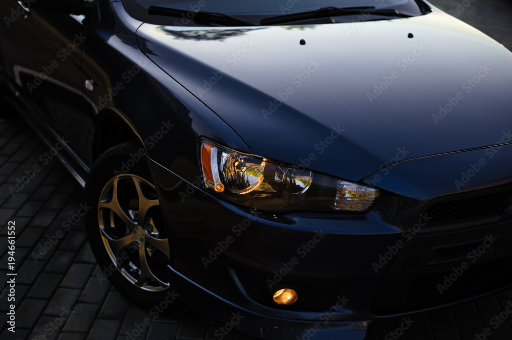 The headlights and hood Blue sports car. Detailed image of the automobile in sunlight
