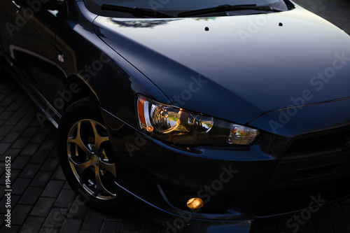 The headlights and hood Blue sports car. Detailed image of the automobile in sunlight