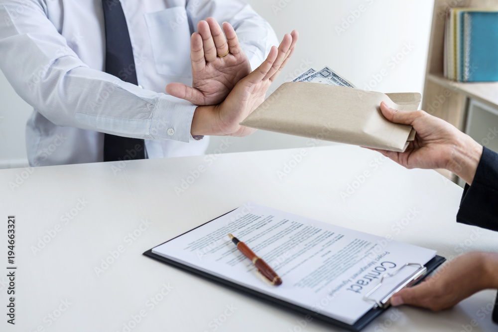 Bribery and corruption concept, Businessman refusing receive money in the envelope to agreement contract, A bribe in the form of dollar bills