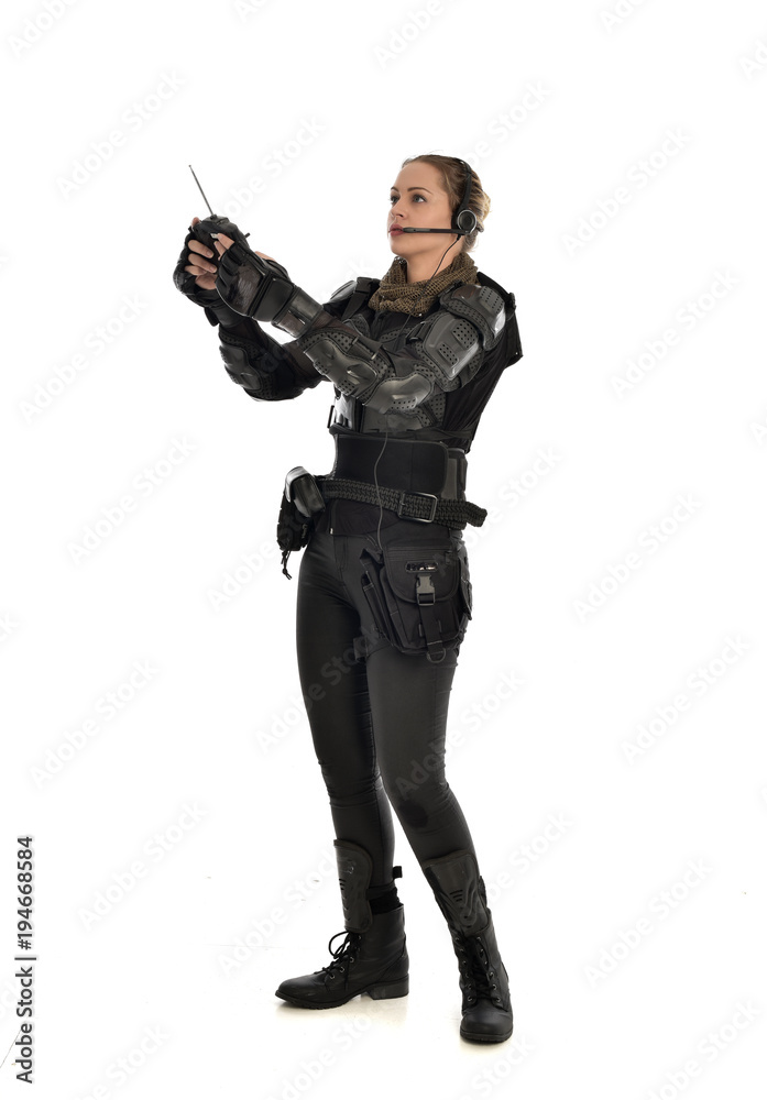 full length portrait of female soldier wearing black tactical armour, holding a remote control, isolated on white studio background. full length portrait of female soldier wearing black tactical armour, holding a remote control, isolated on white studio background.