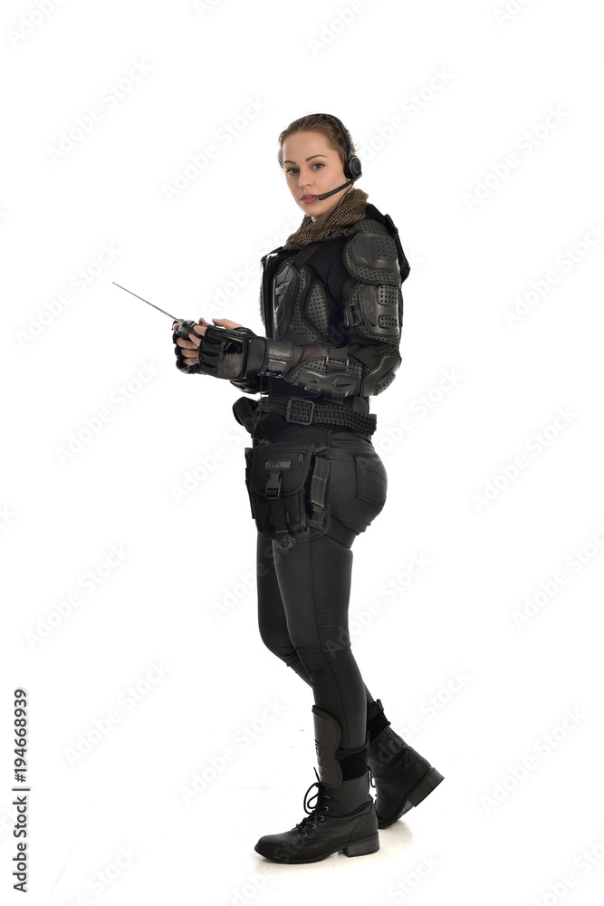 full length portrait of female soldier wearing black tactical armour, holding a remote control, isolated on white studio background. full length portrait of female soldier wearing black tactical armour, holding a remote control, isolated on white studio background.