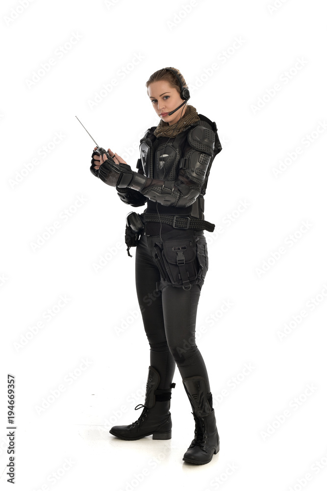 full length portrait of female soldier wearing black tactical armour, holding a remote control, isolated on white studio background. full length portrait of female soldier wearing black tactical armour, holding a remote control, isolated on white studio background.