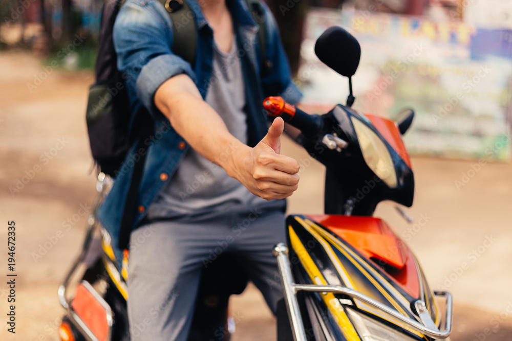 Obraz premium Young happy and handsome male motorcyclist riding on motorbike giving thumbs up and positive.