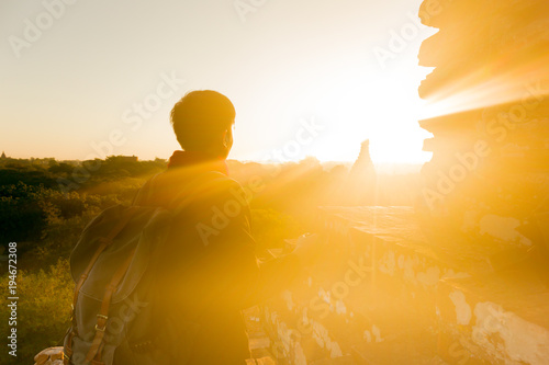 Silhouette of young male backpacker watching sunset and pagoda in Bagan, Burma.