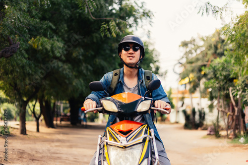 Young happy and handsome male motorcyclist in sunglasses and helmet riding on motorbike.