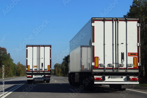 Schilderij op canvas Two trucks on the road in summer against the blue sky