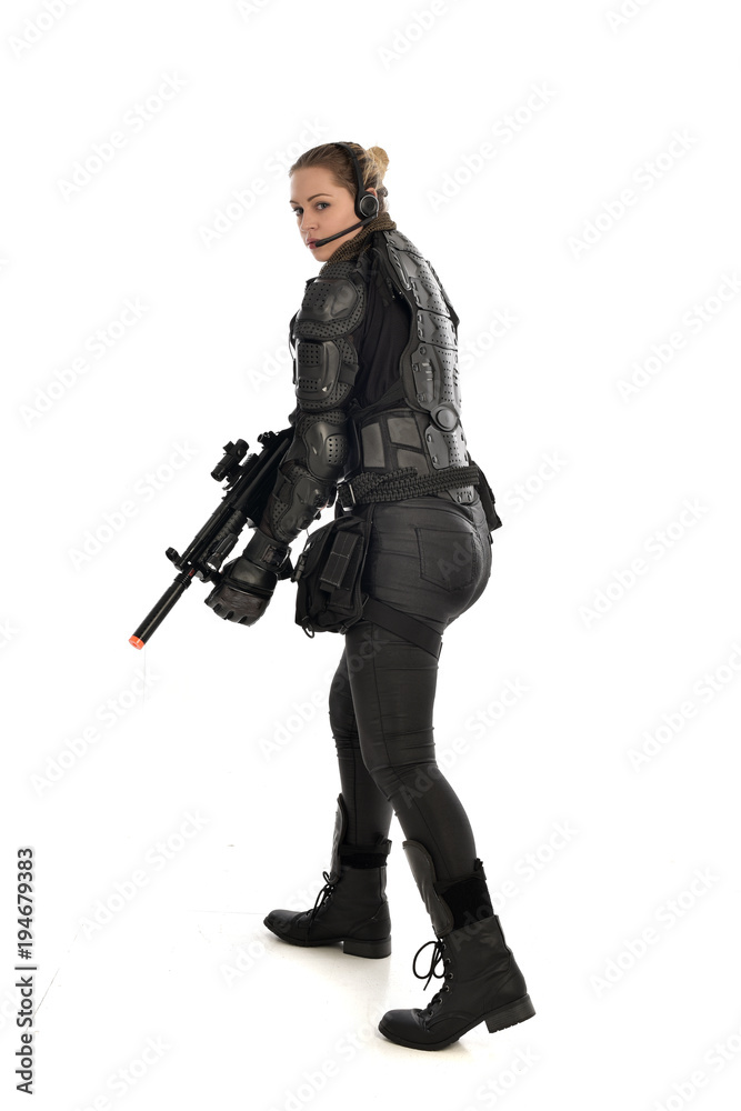 full length portrait of female soldier wearing black tactical armour, holding a rifle gun, isolated on white studio background. full length portrait of female soldier wearing black tactical armour, holding a rifle gun, isolated on white studio background.