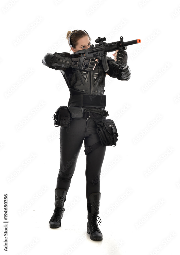 full length portrait of female soldier wearing black tactical armour, holding a rifle gun, isolated on white studio background. full length portrait of female soldier wearing black tactical armour, holding a rifle gun, isolated on white studio background.