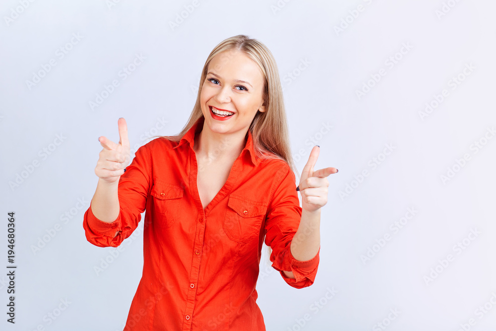 Young blond woman in casual clothes, with positive emotions points to a gray background. Young blond woman in casual clothes, with positive emotions points to a gray background.
