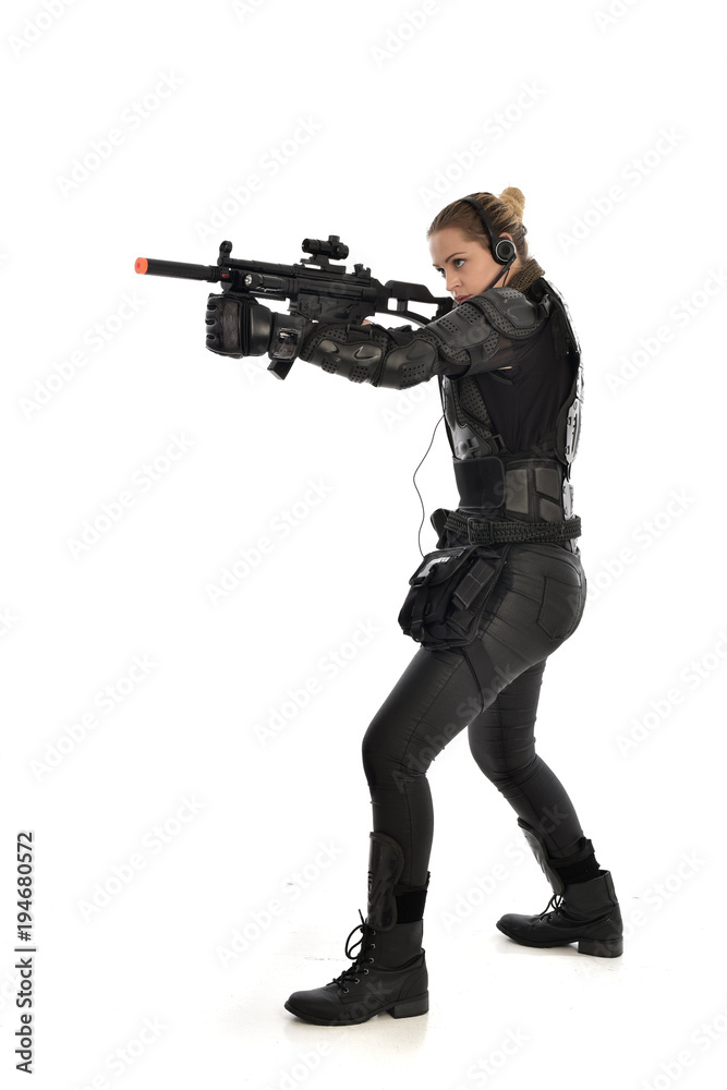 full length portrait of female soldier wearing black tactical armour, holding a rifle gun, isolated on white studio background. full length portrait of female soldier wearing black tactical armour, holding a rifle gun, isolated on white studio background.