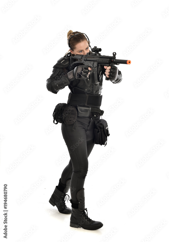 full length portrait of female soldier wearing black tactical armour, holding a rifle gun, isolated on white studio background. full length portrait of female soldier wearing black tactical armour, holding a rifle gun, isolated on white studio background.