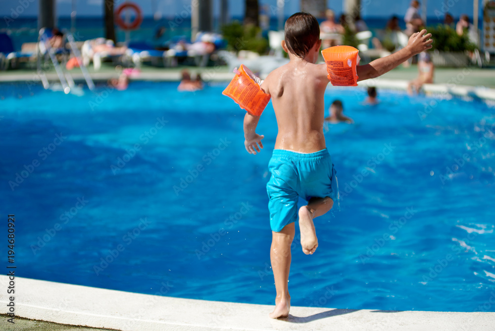 European child running to jump into the pool.