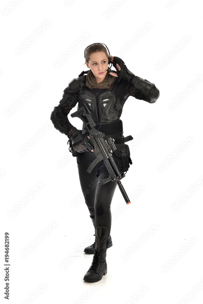 full length portrait of female soldier wearing black tactical armour, holding a rifle gun, isolated on white studio background. full length portrait of female soldier wearing black tactical armour, holding a rifle gun, isolated on white studio background.