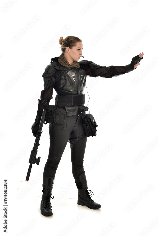 full length portrait of female soldier wearing black tactical armour, holding a rifle gun, isolated on white studio background. full length portrait of female soldier wearing black tactical armour, holding a rifle gun, isolated on white studio background.