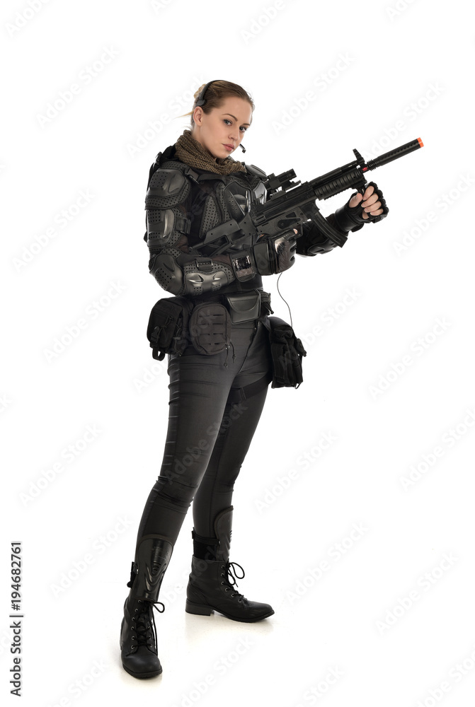 full length portrait of female soldier wearing black tactical armour, holding a rifle gun, isolated on white studio background. full length portrait of female soldier wearing black tactical armour, holding a rifle gun, isolated on white studio background.