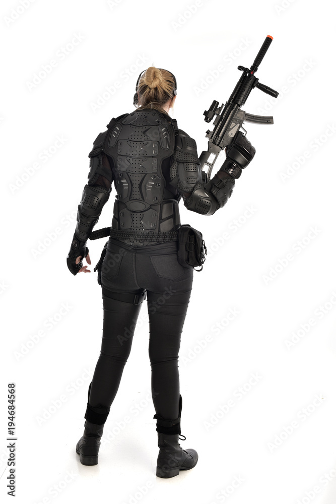 full length portrait of female soldier wearing black tactical armour, holding a rifle gun, isolated on white studio background. full length portrait of female soldier wearing black tactical armour, holding a rifle gun, isolated on white studio background.