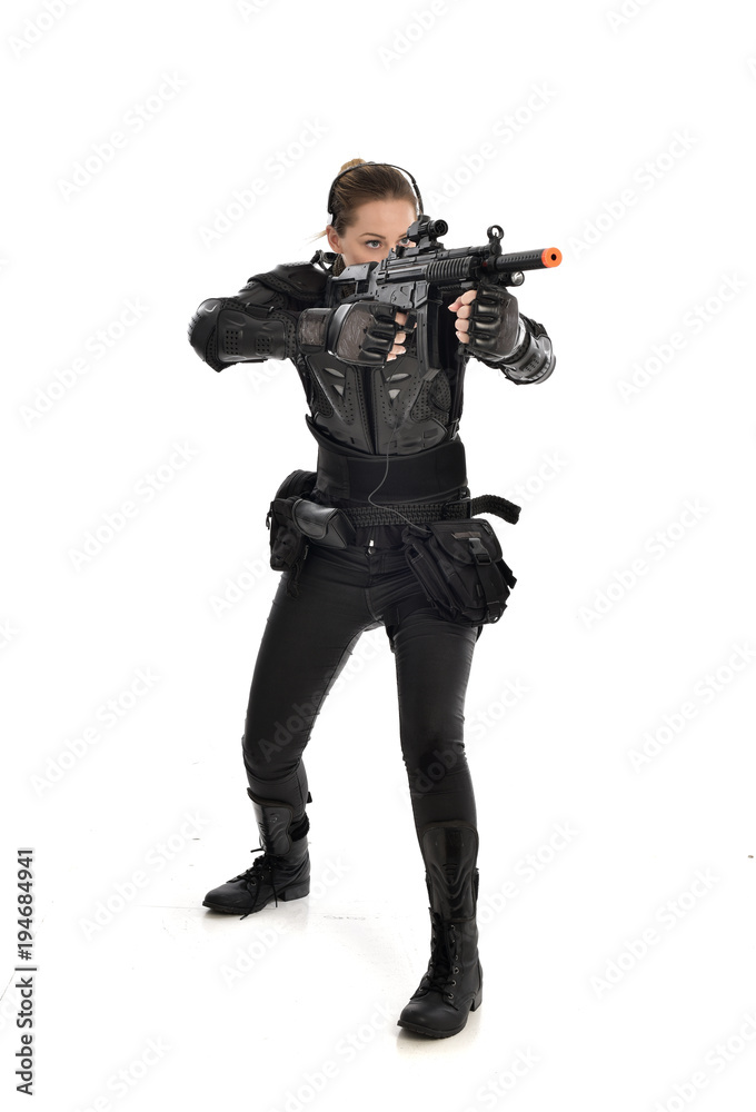 full length portrait of female soldier wearing black tactical armour, holding a rifle gun, isolated on white studio background. full length portrait of female soldier wearing black tactical armour, holding a rifle gun, isolated on white studio background.