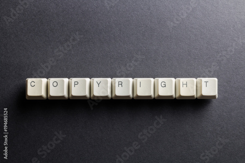 Word copyright made using computer keyboard buttons on a black background. Legal right. IT technology concept.