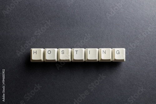 Word hosting made using computer keyboard buttons on a black background. Internet hosting service. IT technology concept.