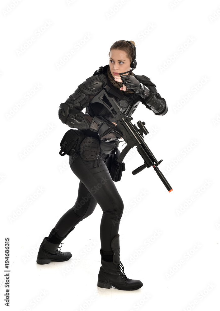 full length portrait of female soldier wearing black tactical armour, holding a rifle gun, isolated on white studio background. full length portrait of female soldier wearing black tactical armour, holding a rifle gun, isolated on white studio background.