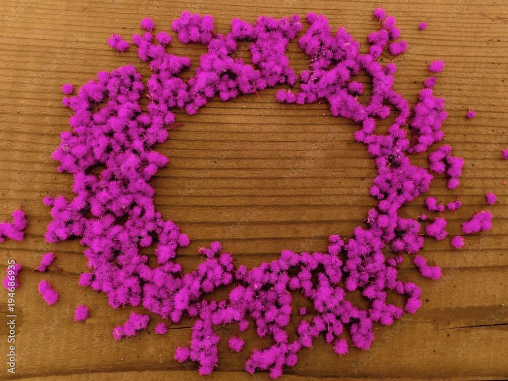 Round pink flowers frame. Round frame of purple pink little flowers on wooden background. Text plase in round frame of pink-purple little flowers on wooden table. Top view of round pink flowers frame