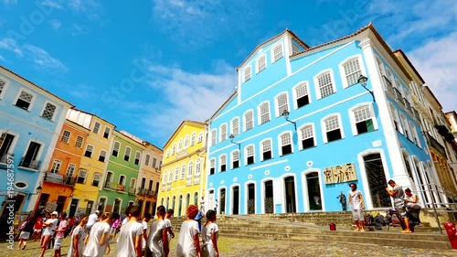 A troupe of dancers follow an instructor infront of colorful buildings photo