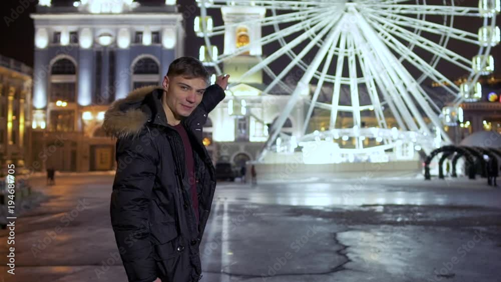 Young guy pretend to move the ferris wheel on background Young guy pretend to move the ferris wheel on background