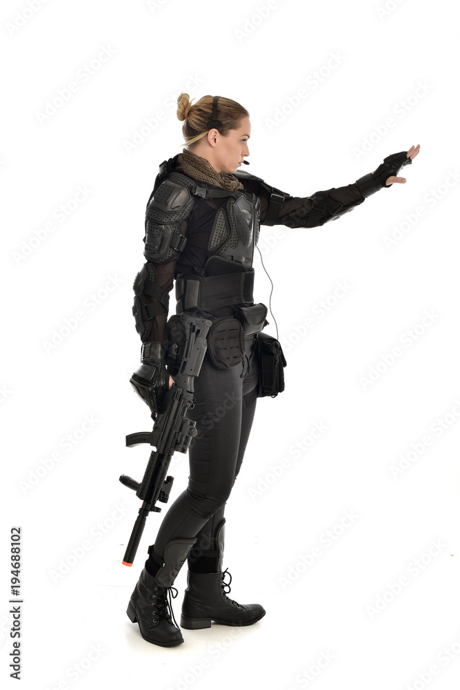 full length portrait of female soldier wearing black tactical armour, holding a rifle gun, isolated on white studio background. full length portrait of female soldier wearing black tactical armour, holding a rifle gun, isolated on white studio background.