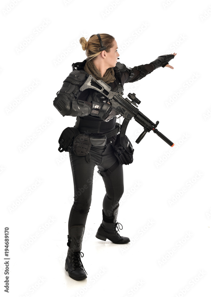 full length portrait of female soldier wearing black tactical armour, holding a rifle gun, isolated on white studio background. full length portrait of female soldier wearing black tactical armour, holding a rifle gun, isolated on white studio background.