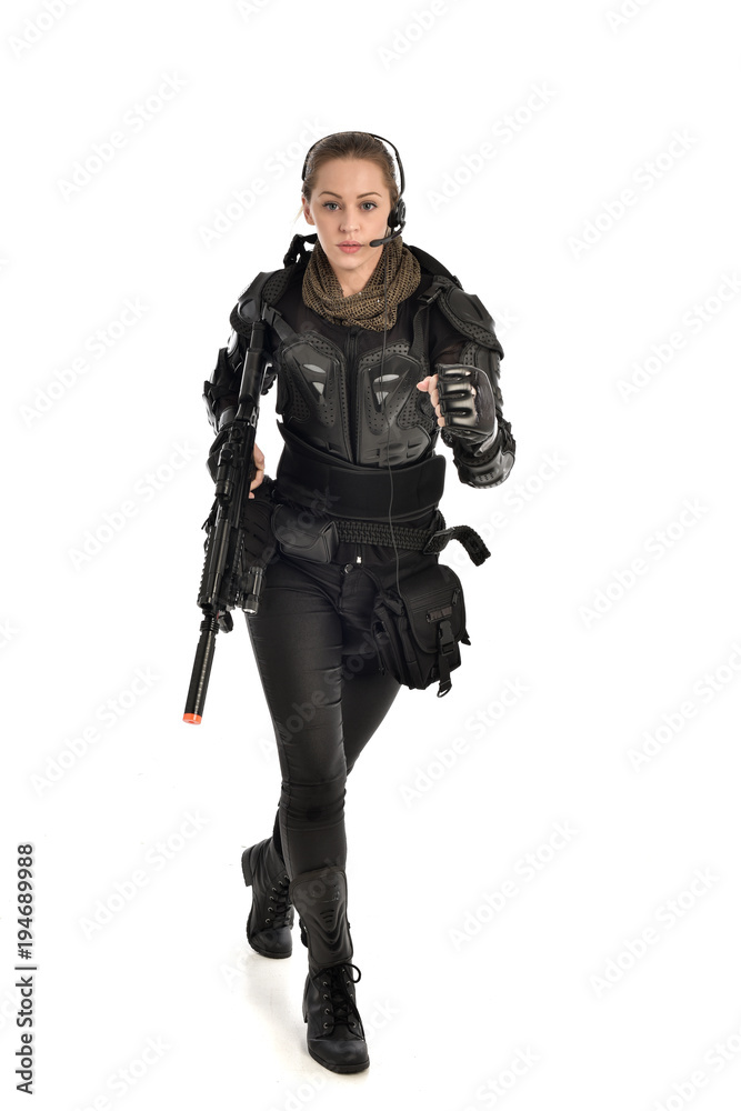 full length portrait of female  soldier wearing black  tactical armour, holding a rifle gun, isolated on white studio background.