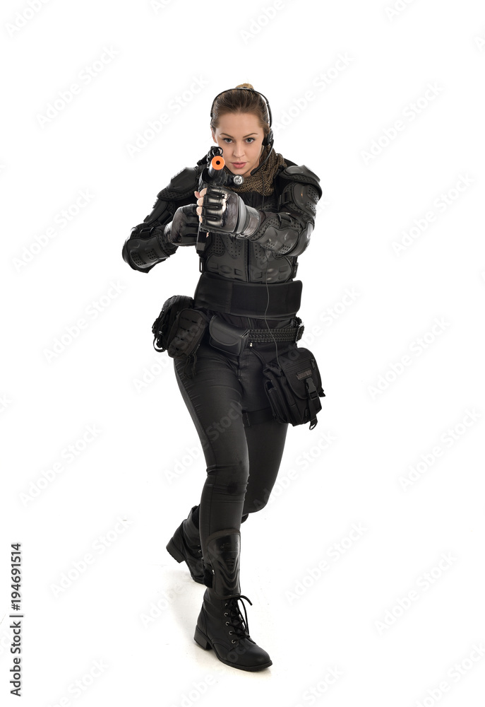 full length portrait of female  soldier wearing black  tactical armour, holding a rifle gun, isolated on white studio background.