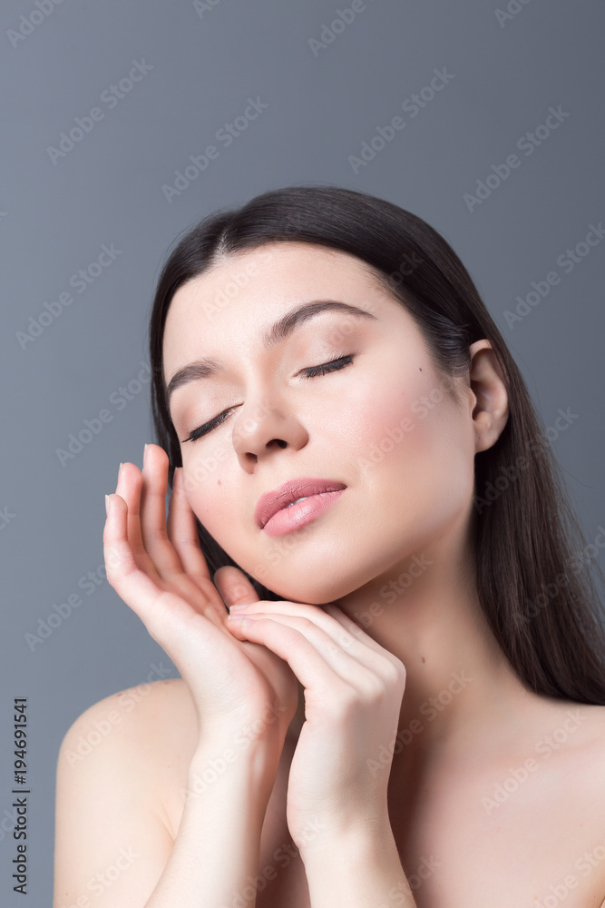 Beautiful woman face and hands close up on grey studio background Beautiful woman face and hands close up on grey studio background