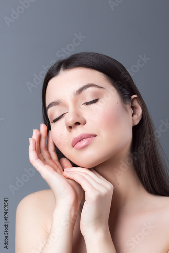 Beautiful woman face and hands close up on grey studio background