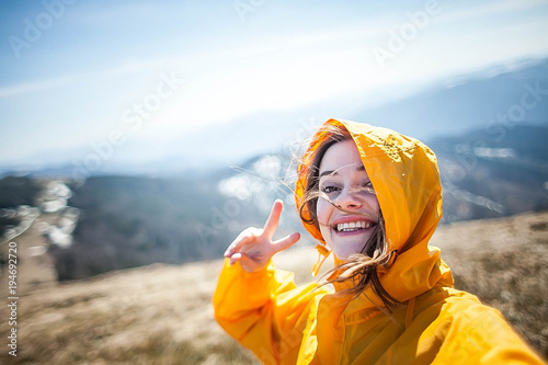A funny girl makes a selfie in the mountains.Hiker makes a selfie uses the phone. Traveler make selfie on mobile phone at mountain outdoor. 