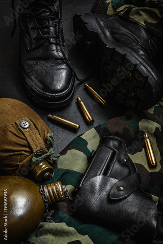 Army uniform military boots, boots, pants, bowler, pistol in holster on a dark background with copy space workspace flat lay top view © shintartanya