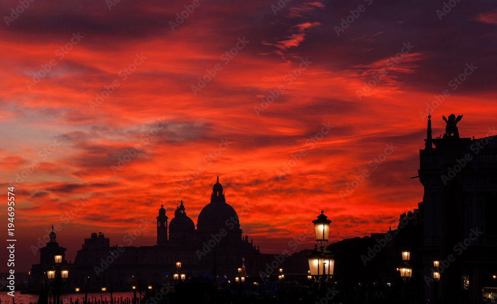 Red blood sky sunset over Venice Lagoon with Salute Basilica domes Saint Mark Lion and lamps