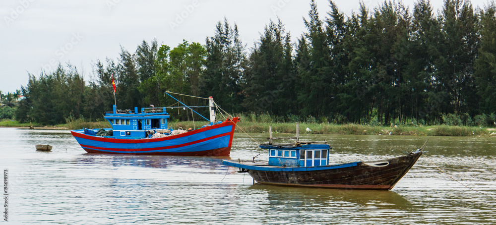 two fishing boats anchored on the side of the river