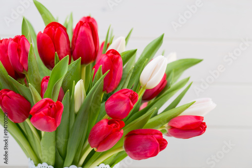 Fresh red tulip flowers bouquet on shelf in front of wooden wall. © gitusik