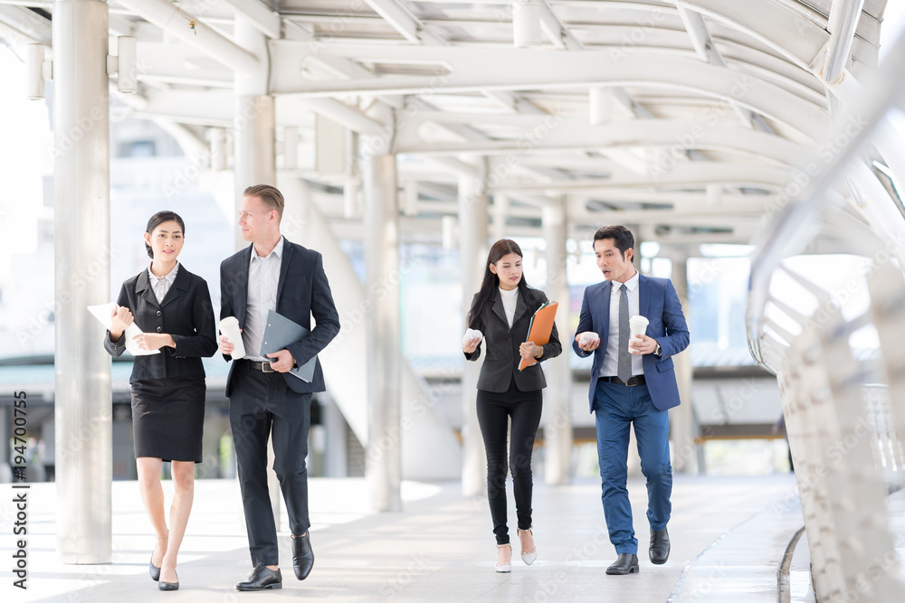 Quick Briefing Before Meeting. Group of Cheerful Young Business People Talking to each other while walking outdoors Quick Briefing Before Meeting. Group of Cheerful Young Business People Talking to each other while walking outdoors